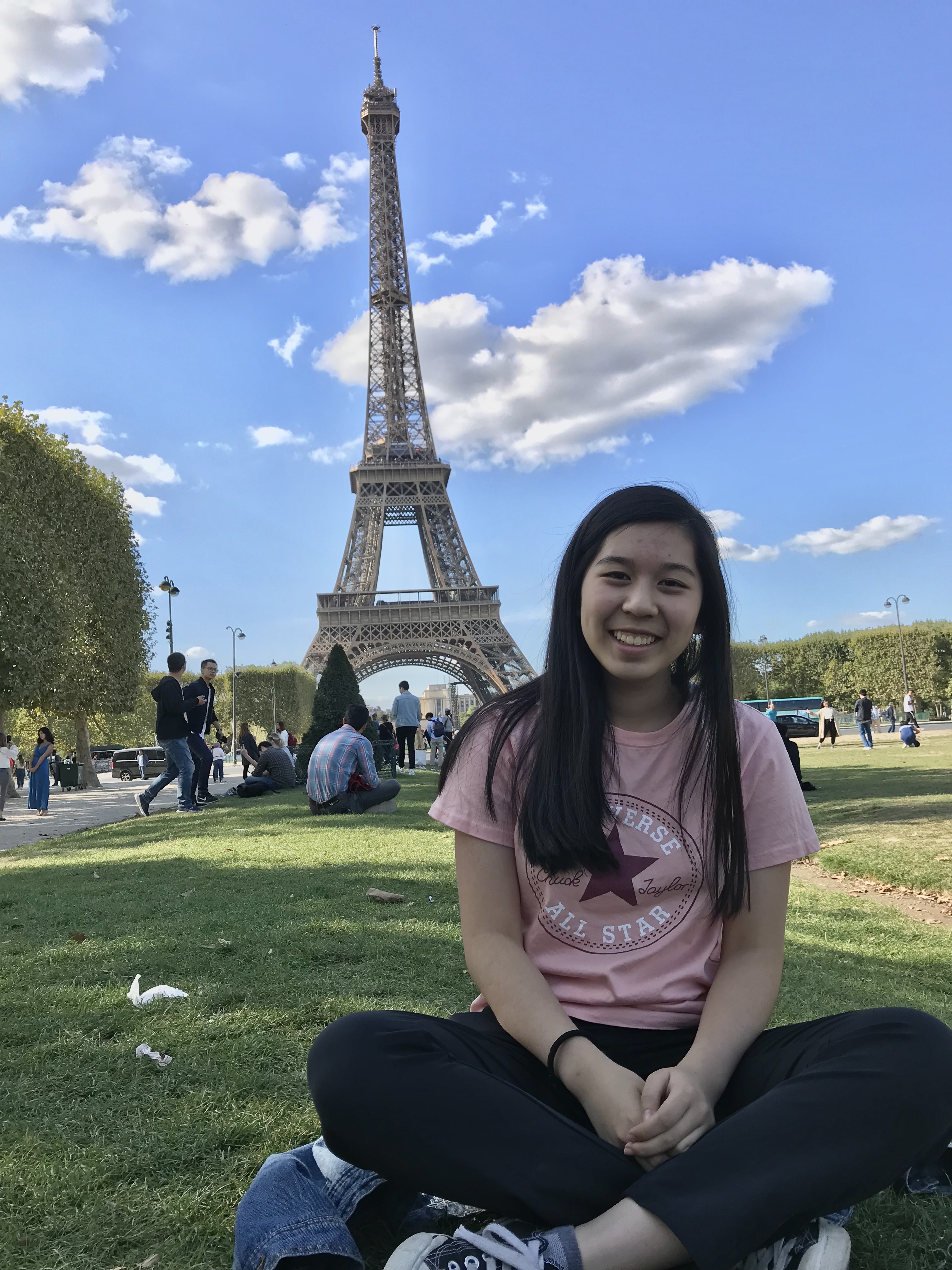 Jocelyn wearing coral t-shirt sitting in front of the Eiffel Tower